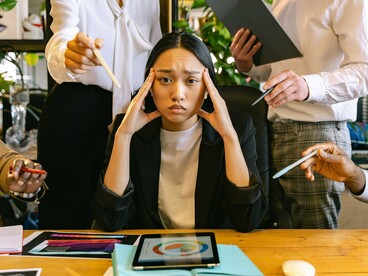 An employee receiving input from multiple coworkers at the same time, reflecting the demands of a collaborative workplace