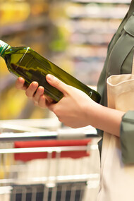 A woman checking the price of olive oil in the market