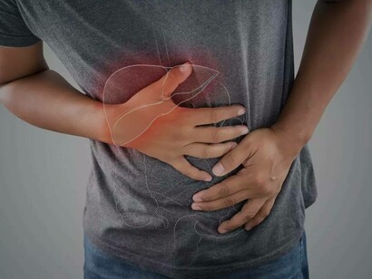 A man places a hand at the source of the pain where the liver is typically located