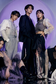 A K-pop-inspired group styled in layered monochrome looks, representing the theatrical fashion narratives central to idol culture