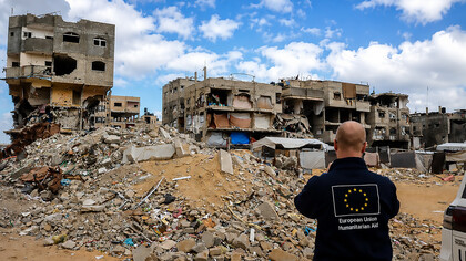 An aid worker surveys the devastation in Gaza, where humanitarian assistance remains a vital lifeline for communities struggling amid widespread destruction and displacement