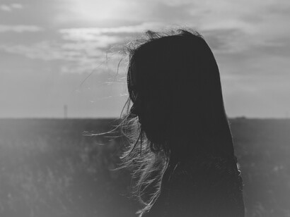 El viento juega con el pelo de una mujer paseando en una pradera