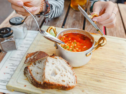 A woman savors traditional Hungarian goulash soup served in a pot at a charming outdoor restaurant