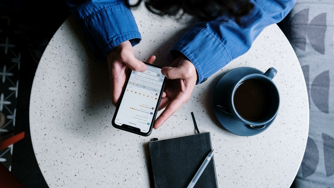 A person sat at a table using social media on a mobile phone
