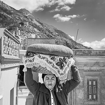 Grecia, Karpathos, 2024. Donna porta in chiesa due pani pasquali artos per le celebrazioni della Pasqua ortodossa. Foto di Stefano Torrione, gentilmente concesse