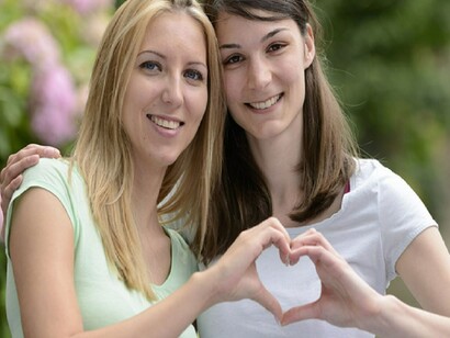 Pareja de mujeres hacen un corazón con sus manos