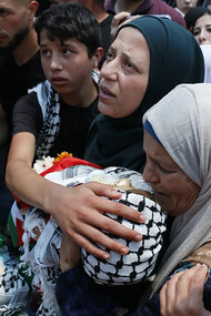 A group of people gathered together, with women visibly grieving, amid the Gaza conflict