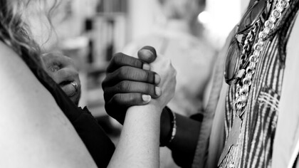 A grayscale photo of a man and woman holding hands, symbolizing connection and unity