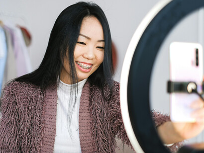 A beauty influencer applying makeup while live streaming on her smartphone