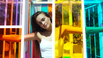 Modelo detrás de una vitrinas de distintos colores. Un color bien elegido puede enfatizar tu mirada, iluminar tu cara o potenciar el brillo de tu cabello