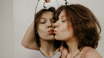 Mulher beija seu reflexo no espelho