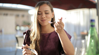 A woman in purple enjoys her meal, taking time to savor each bite