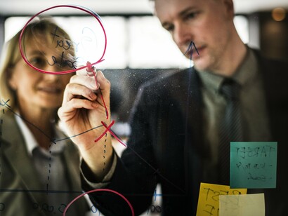 A team collaborates in a brainstorming session using sticky notes and diagrams to visualize their strategy, illustrating the hybrid approach many companies are now taking, combining elements of different methodologies, including Agile