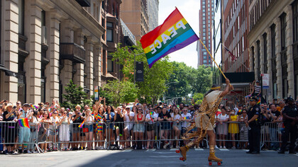 Membro da comunidade LGBTQIAPN+ corre com bandeira escrito Paz na parada da diversidade de Nova Iorque nos Estados Unidos da América
