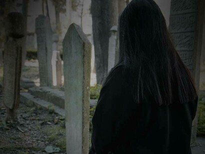 A woman praying for the buried at the cemetery 