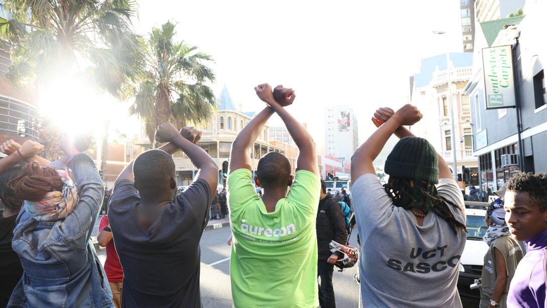 A group of students raise their hands to signal that they have come in peace