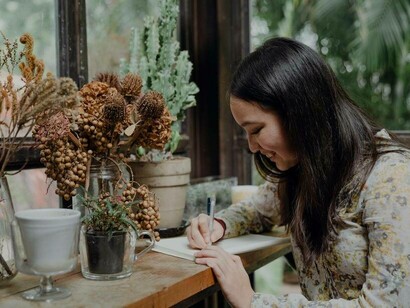 A writer smiling as she jots down her thoughts and feelings