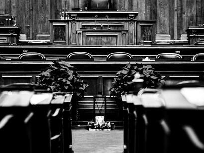 Plano en blanco y negro centrado hacia el estrado principal de una sala de debates de madera