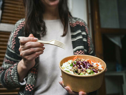 A woman enjoying a seafood salad, served in innovative edible packaging, showcasing sustainable food packaging solutions
