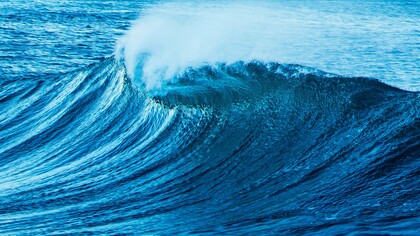 The roar of the tides: a powerful ocean wave curls and crashes, its deep blue waters shimmering under the light, reflecting both motion and depth, mirroring the ever-changing currents of thought and emotion