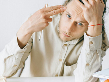 Young office worker experiencing stress and mental exhaustion at his desk, highlighting workplace burnout and anxiety among Gen-Z professionals