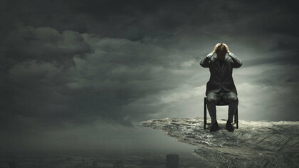 A man stuck in his suffering, sitting on a cliff...