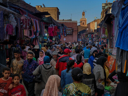 People walking and shopping at a market in Morocco. The cognitive advantages of multilingualism may also have contributed to Moroccan inhabitants' progress