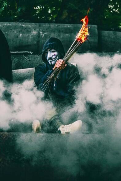 A masked figure setting objects on fire