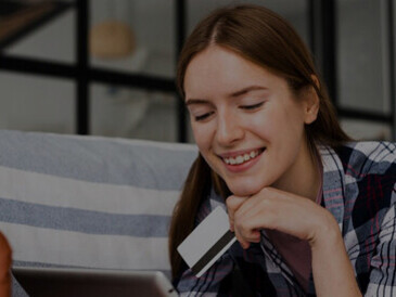 Amidst the pandemic's push for digitalization, a woman is captured engaged in online shopping on her tablet, holding a credit card, illustrating the accelerated growth of e-commerce during COVID-19