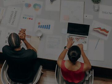 Amidst a lively office ambiance, a woman shares insights and ideas over coffee with colleagues, epitomizing collaborative teamwork and entrepreneurial synergy