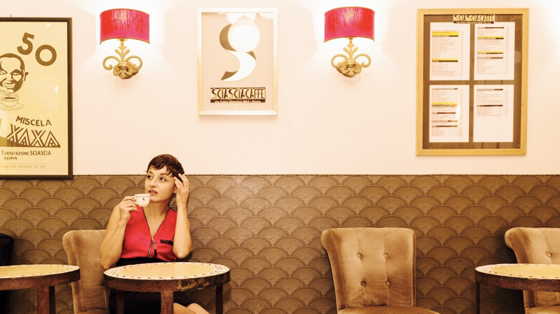 A woman drinking coffee in a cafe in Rome, Italy