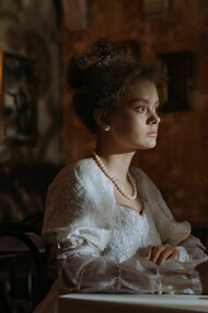 A noblewoman writing by candlelight in an elegant historic interior