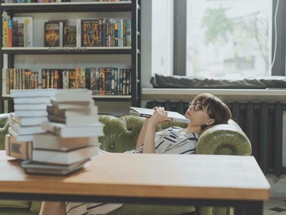 Donna che riflette su ciò che ha letto stesa sul divano