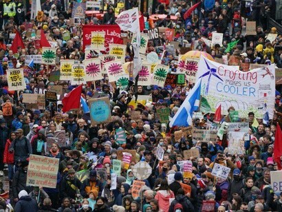 Thousands of protestors carrying signs and banners calling for changes concerning the government environmental policy in Glasgow, Scotland