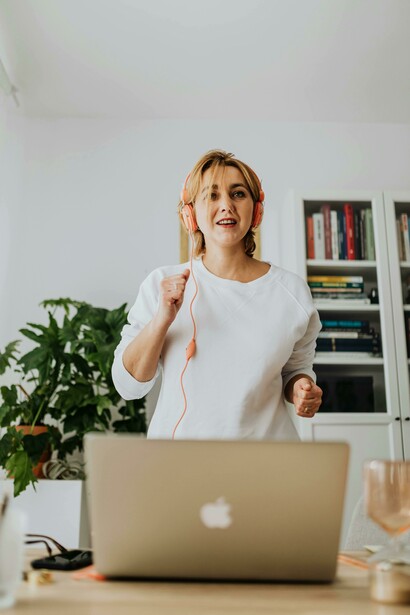 Listening to music through headphones, a woman exercises at home and engages in language learning at the same time
