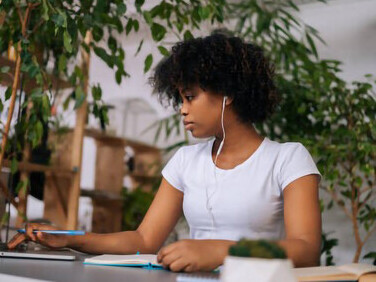 A female freelance designer, in a biophilic workspace, passionately generates fresh ideas, crafts a business plan, and works remotely on her laptop