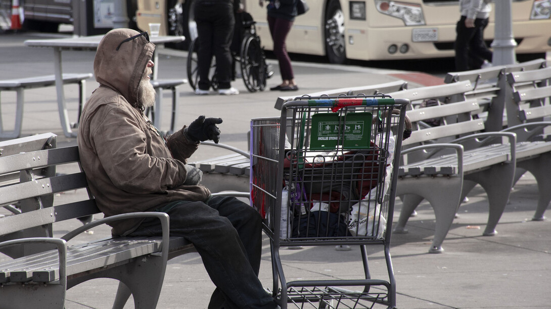Hombre sin hogar descansa en una banca