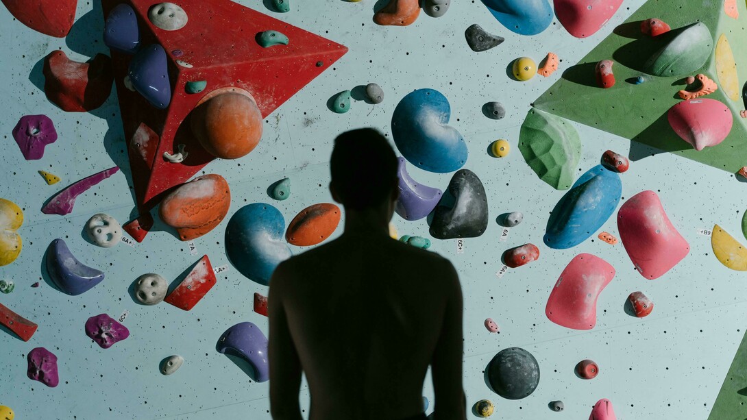 A silhouette of a man standing before a climbing wall, preparing to climb