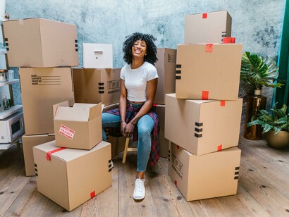 A happy woman sitting on the floor among moving boxes, marking a new beginning