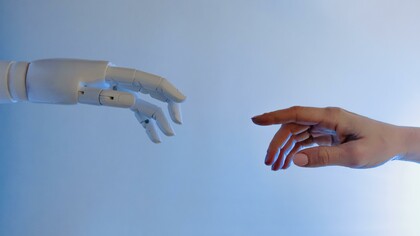 Mão de robô representando a inteligência artificial e mão de um humano