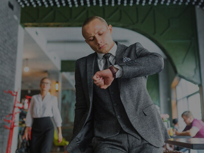 A businessman checking his wristwatch, exemplifying time management in a busy corporate environment