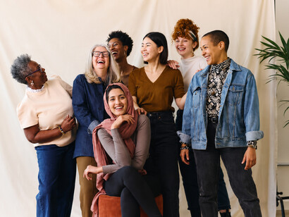 Smiling women from different ethnic backgrounds and age groups pose together, reflecting unity, diversity, and empowerment