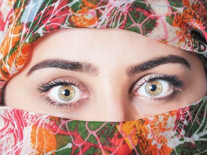 A woman wearing a scarf only revealing her eyes that are of a lighter shade of brown that are unique thanks to the Keratopigmentation procedure