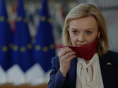 British Prime Minister Liz Truss takes off her protective face mask as she arrives for an EU foreign ministers meeting in Brussels  