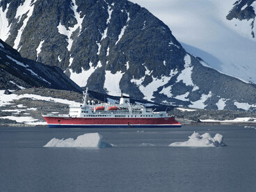 Antarctica: view of an ice sheet and snowcapped mountains under dark clouds