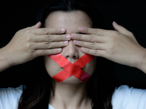 A young woman with adhesive tape over her mouth symbolizes censorship, representing the struggle for freedom of speech and press in the context of protecting fundamental freedoms