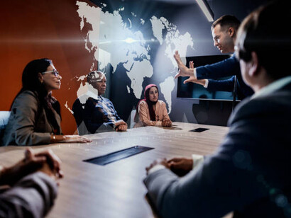 In an office meeting, a man utilizes a hologram to address global challenges and discuss collaborative solutions on an international scale