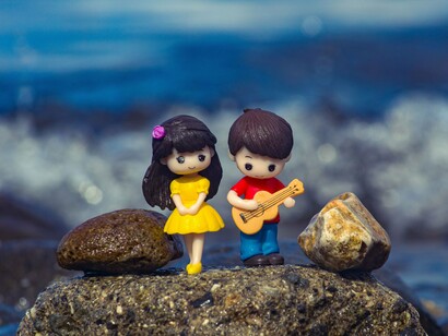 A pair of figurines sharing a simple moment together, representing that love is built through shared experiences rather than grand gestures