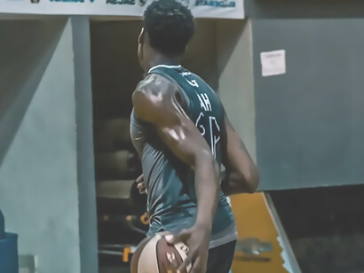 In the grip of his hand, a young man confidently cradles a basketball, radiating an aura of sportsmanship and anticipation for the game ahead