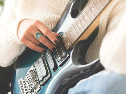 Mujer toca suevamente las cuerdas de una guitarra eléctrica